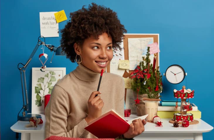 woman holding a notebook and a pencil, thinking