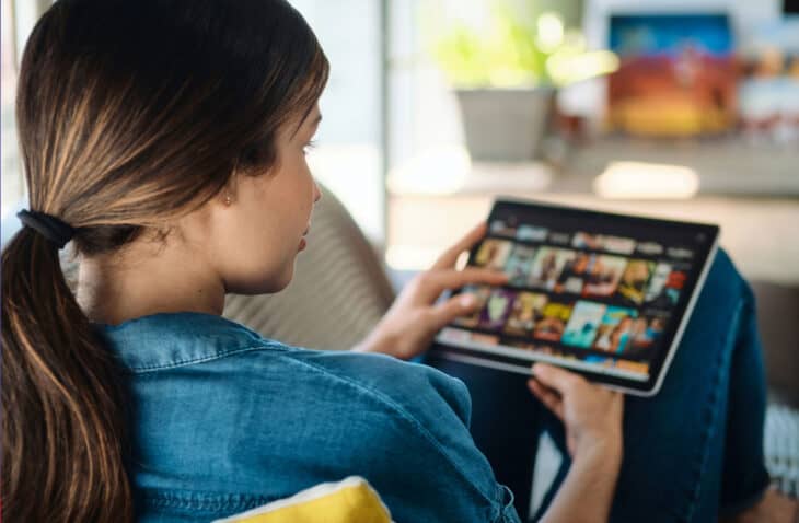 Woman on couch looking through options on her tablet