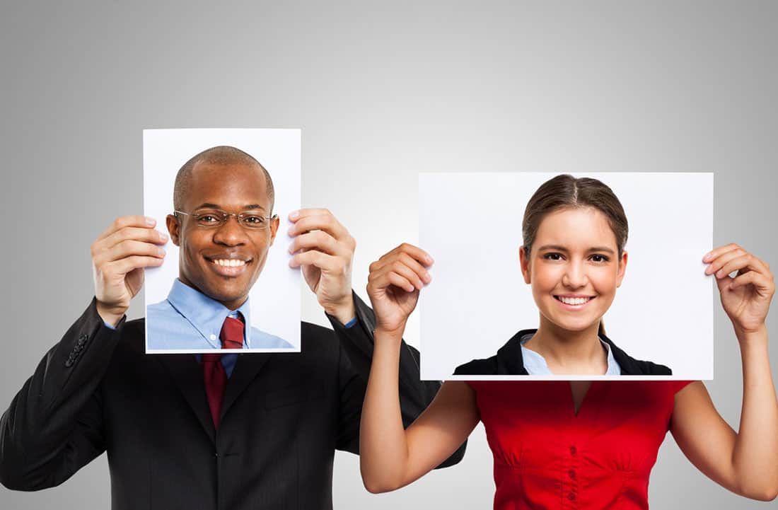 woman and man holding up pictures of other people's faces to their face