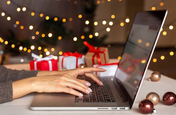 mujer escribiendo en una computadora portátil, regalos en el fondo