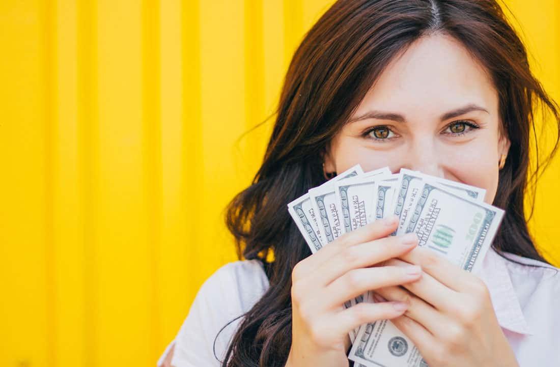 Mujer sosteniendo dinero frente a su cara