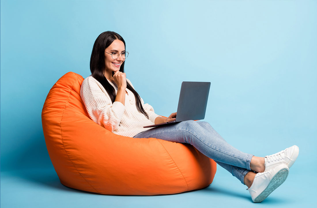 Mujer con computadora portátil sentada en una bolsa de frijoles