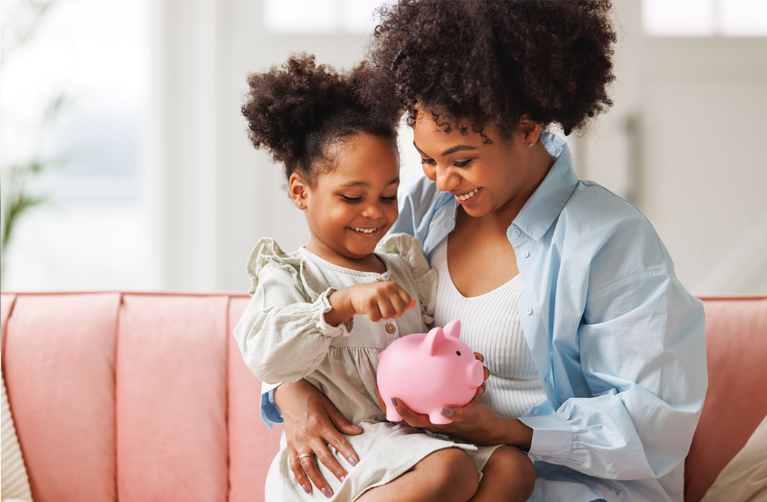Mom and daughter putting money in a piggy bank