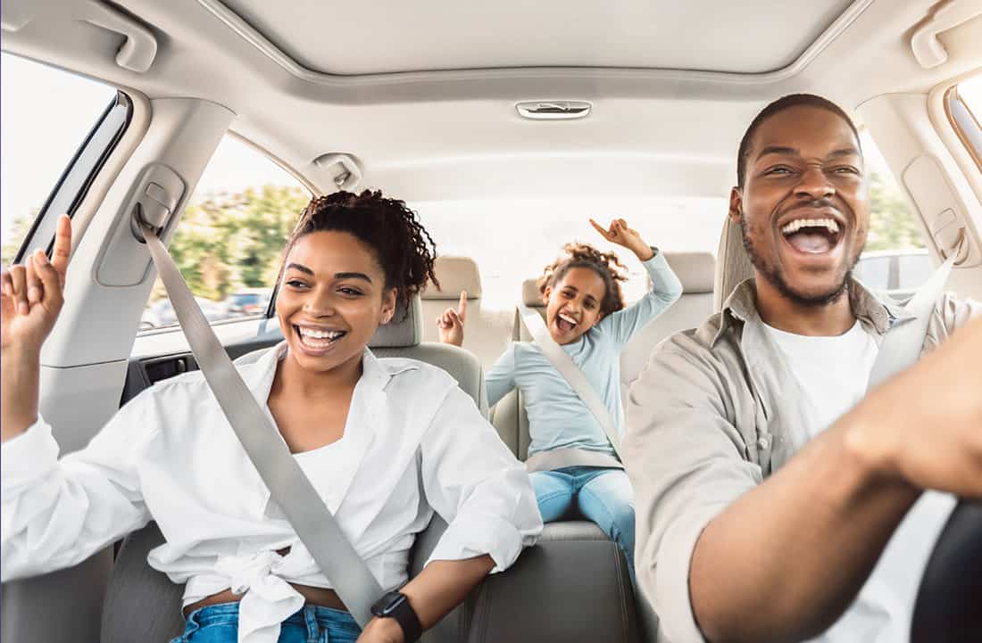 Family of three smiling in the car