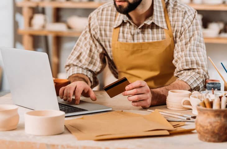 Pottery business owner using his card to make online purchase