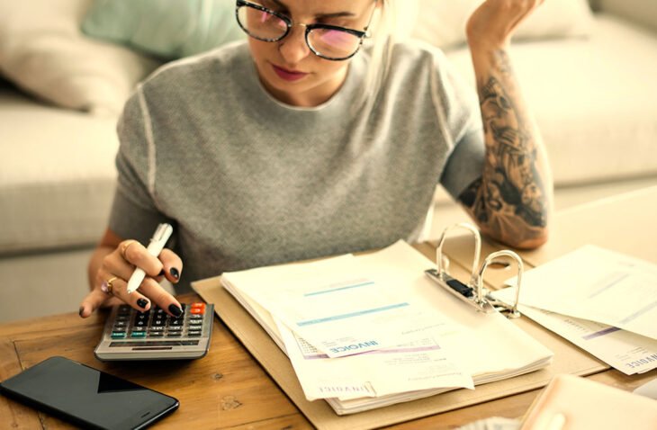 Mujer usando una calculadora y mirando facturas