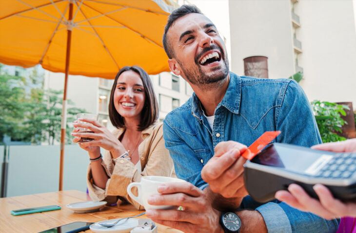 man and woman at coffee shop, he's paying with a tap to pay card