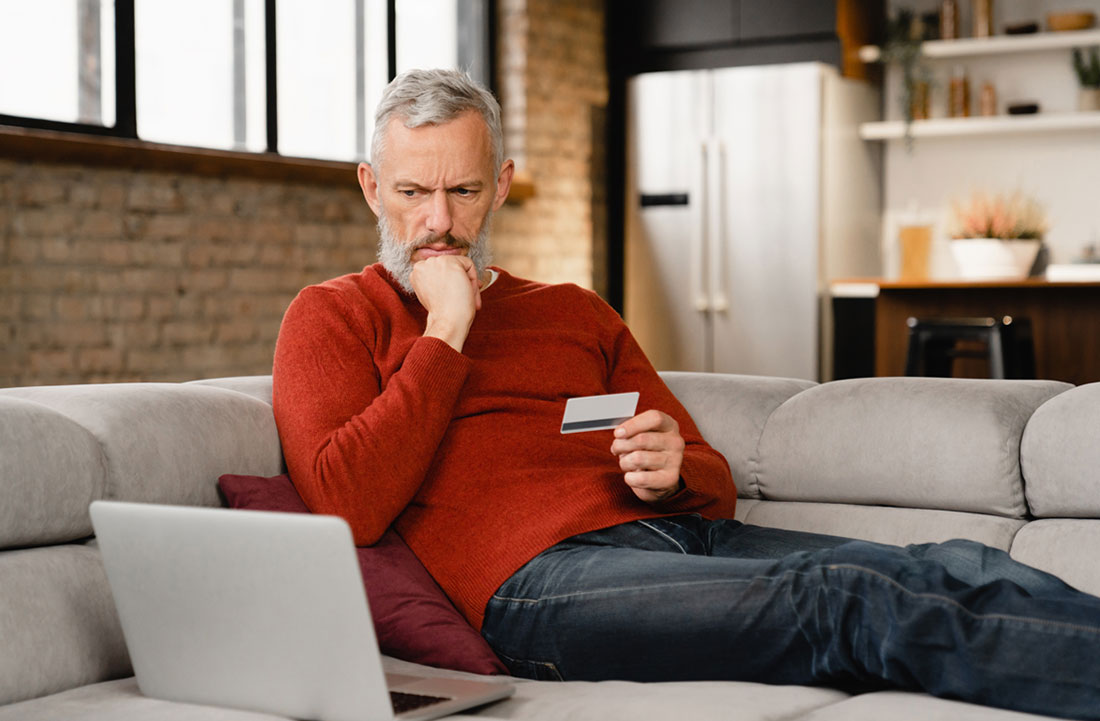 man holding a card looking confused at his computer