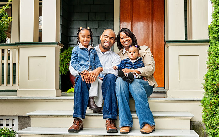 Family sitting on front steps of house