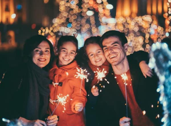 A family of four smiling while holding sparklers