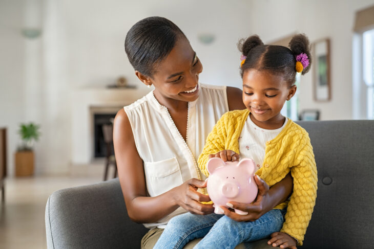 Adult and child using a piggy bank.
