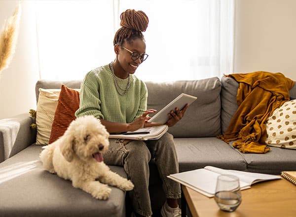 Woman looking at tablet and smiling next to dog