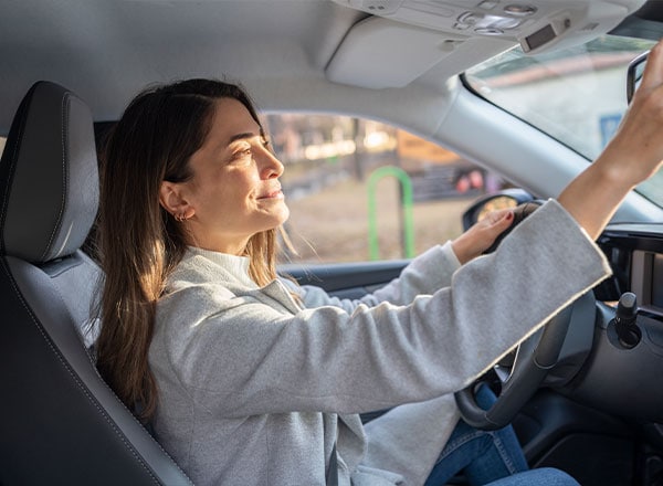 woman in car adjusting mirror