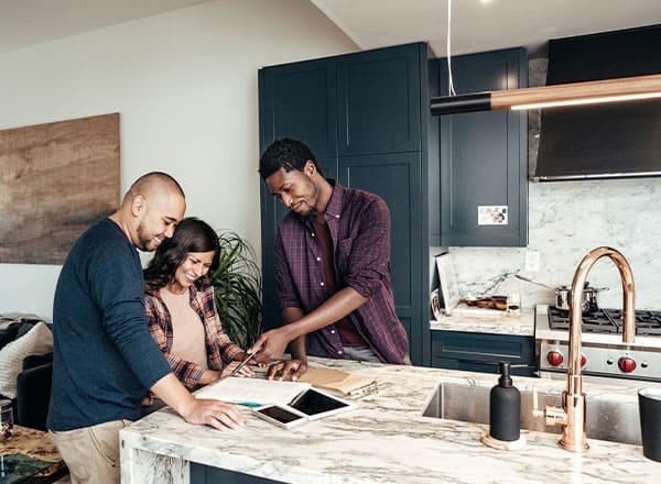 Three people in a kitchen, examining paperwork together