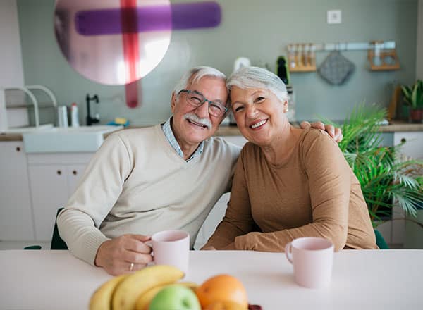 Two elderly individuals seated at a table, smiling