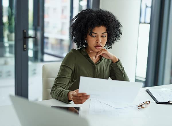 Mujer sosteniendo un trozo de papel y leyendo atentamente su contenido.