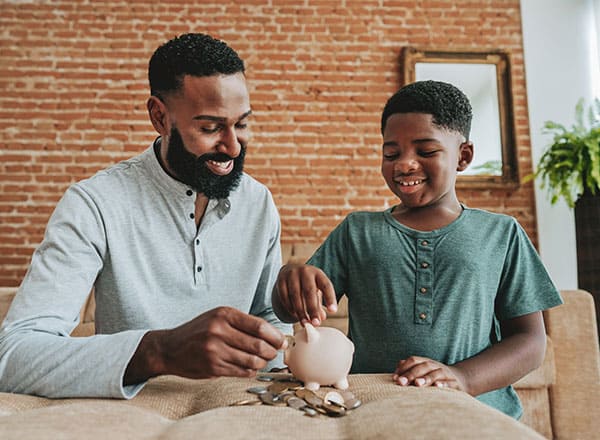 Father and son putting money in piggy bank