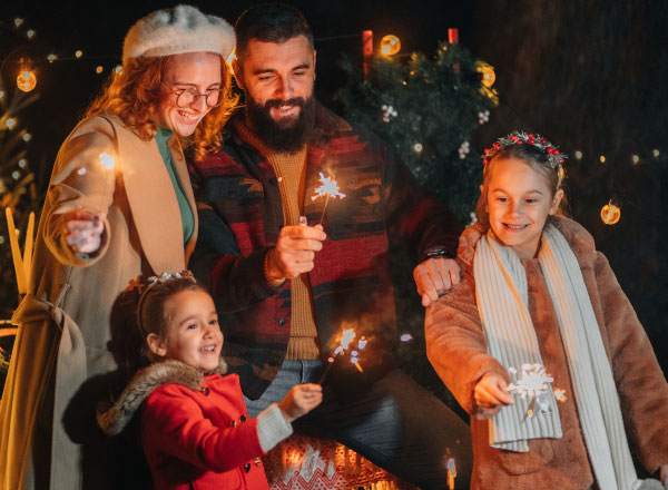 A family of four smiling while holding sparklers