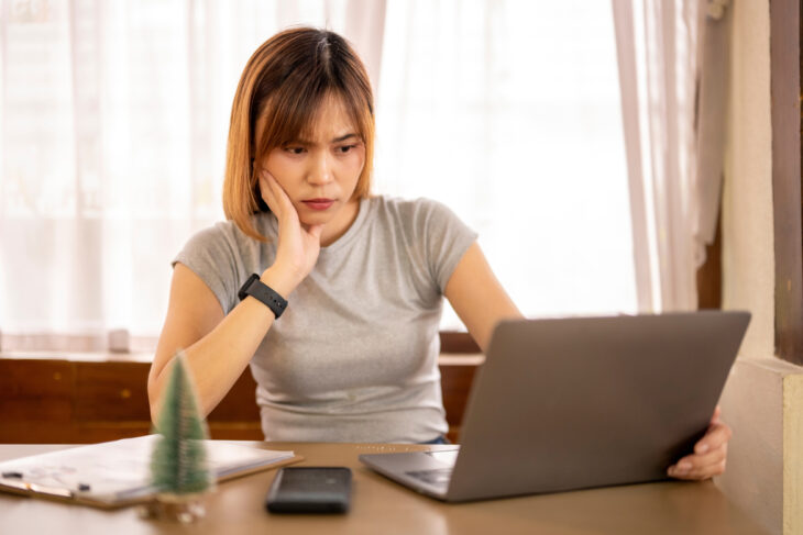 Woman looking at her computer screen in a concerned way.