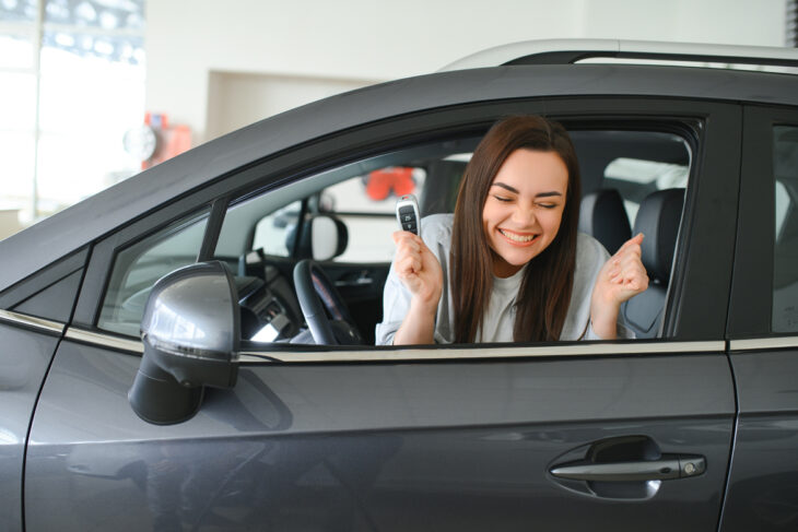 Woman excited driving new car.