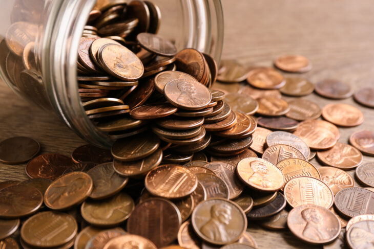 Monedas cayendo del frasco de vidrio