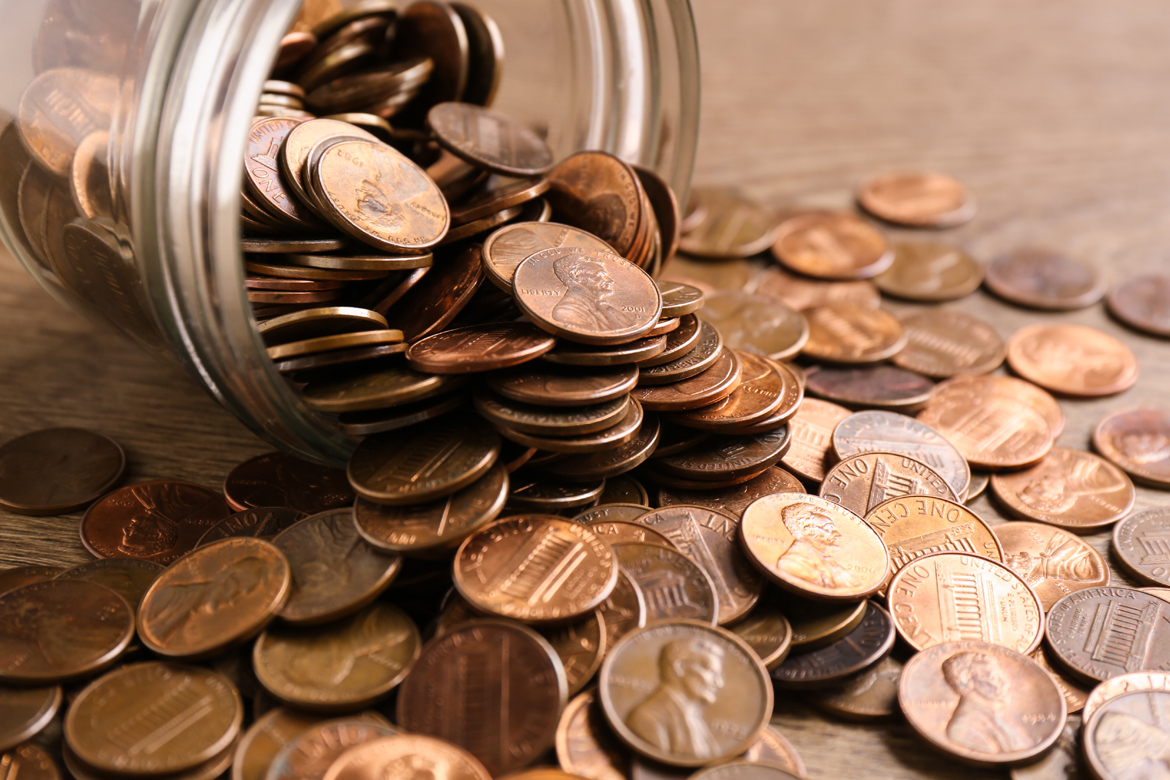 Monedas cayendo del frasco de vidrio