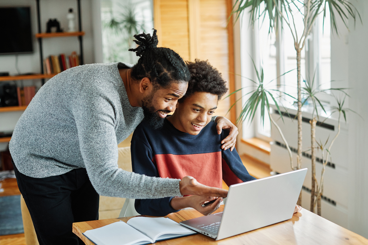 Adult and teenager reviewing financial details on computer
