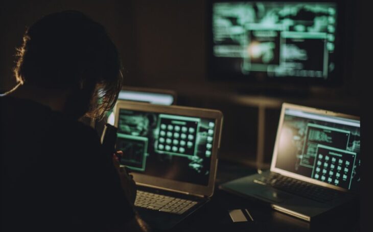 Hacker mirando pantallas de computadora.