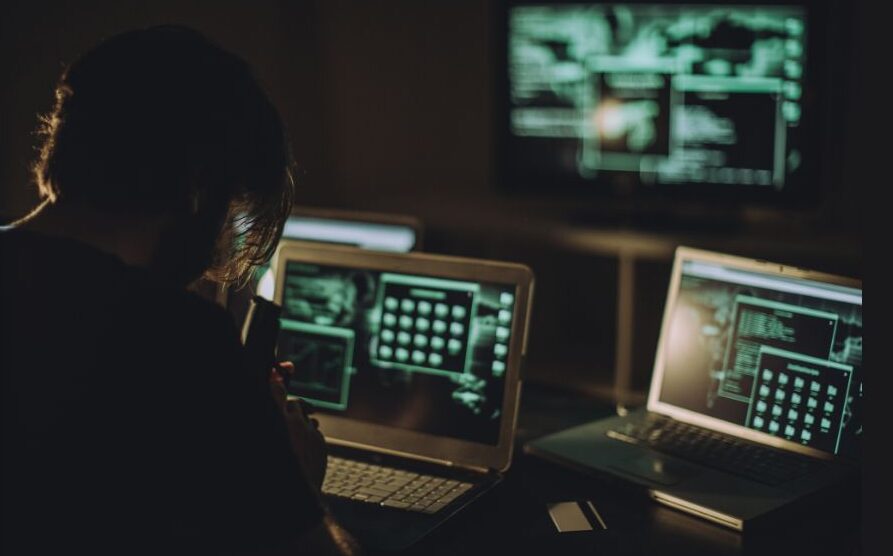 Hacker looking at computer screens.