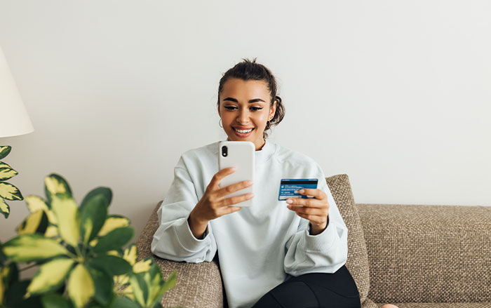 Mujer sosteniendo tarjeta y teléfono celular