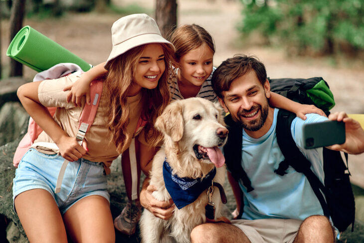 A family taking a photo with their dog on vacation.